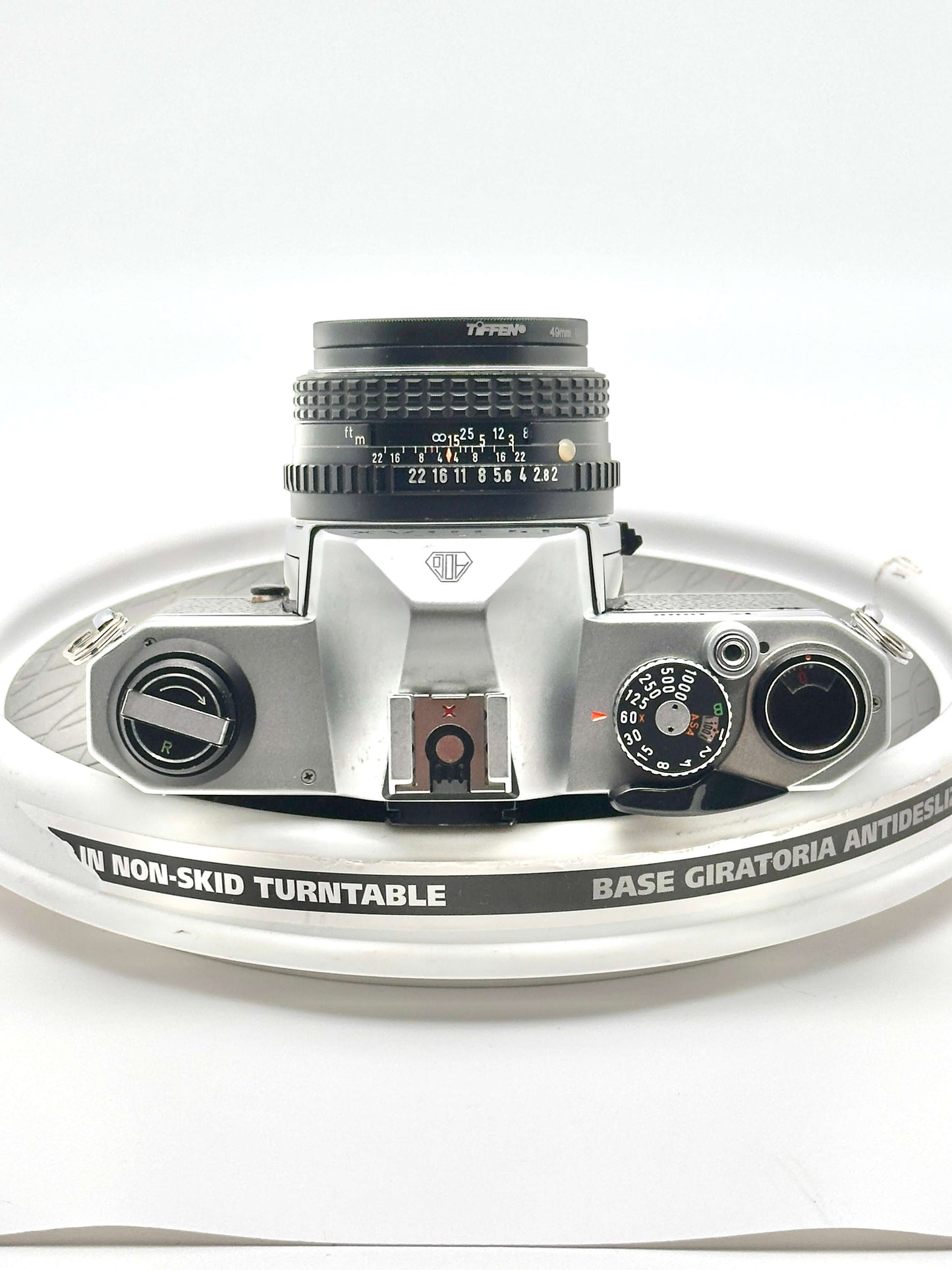 Close-up of a Pentax K1000 35mm film camera on a non-skid turntable, showcasing its lens and features.