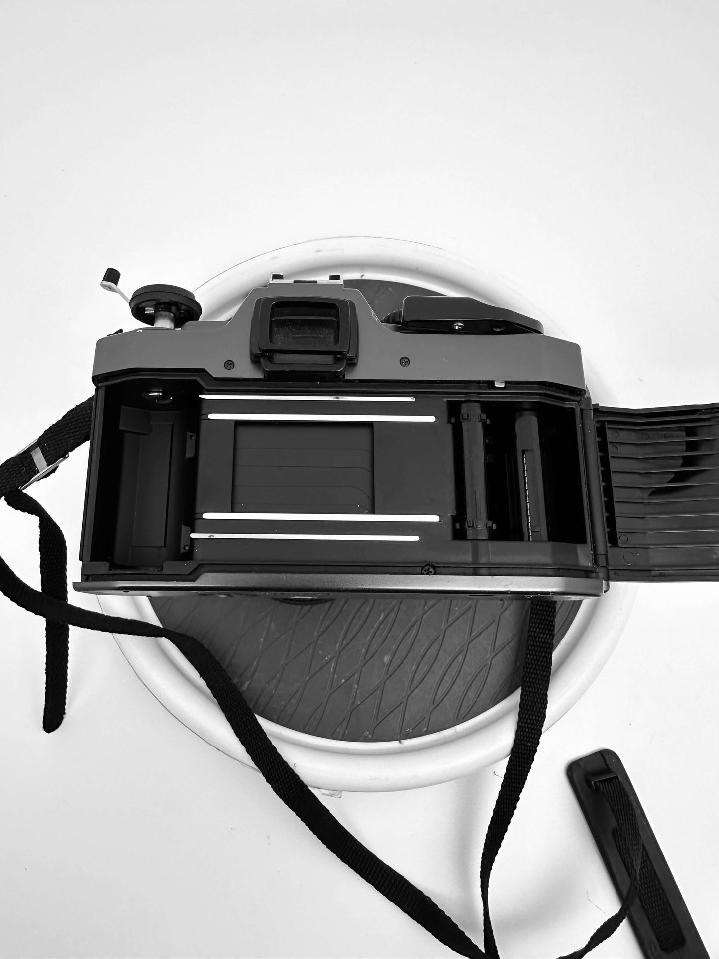 Olympus OM 2000 film camera with its back open, showing the film compartment and winding mechanism.