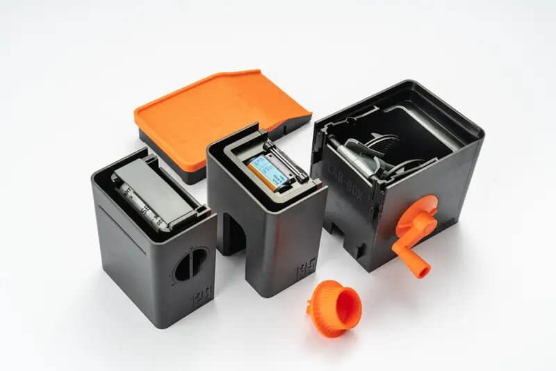 Black plastic ink cartridge holders with orange caps and handles, designed for easy replacement.