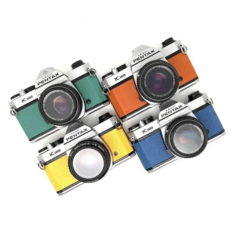 A set of vintage pentax k1000 and k3000 film cameras with colorful leather grips in green, orange, yellow, and blue.