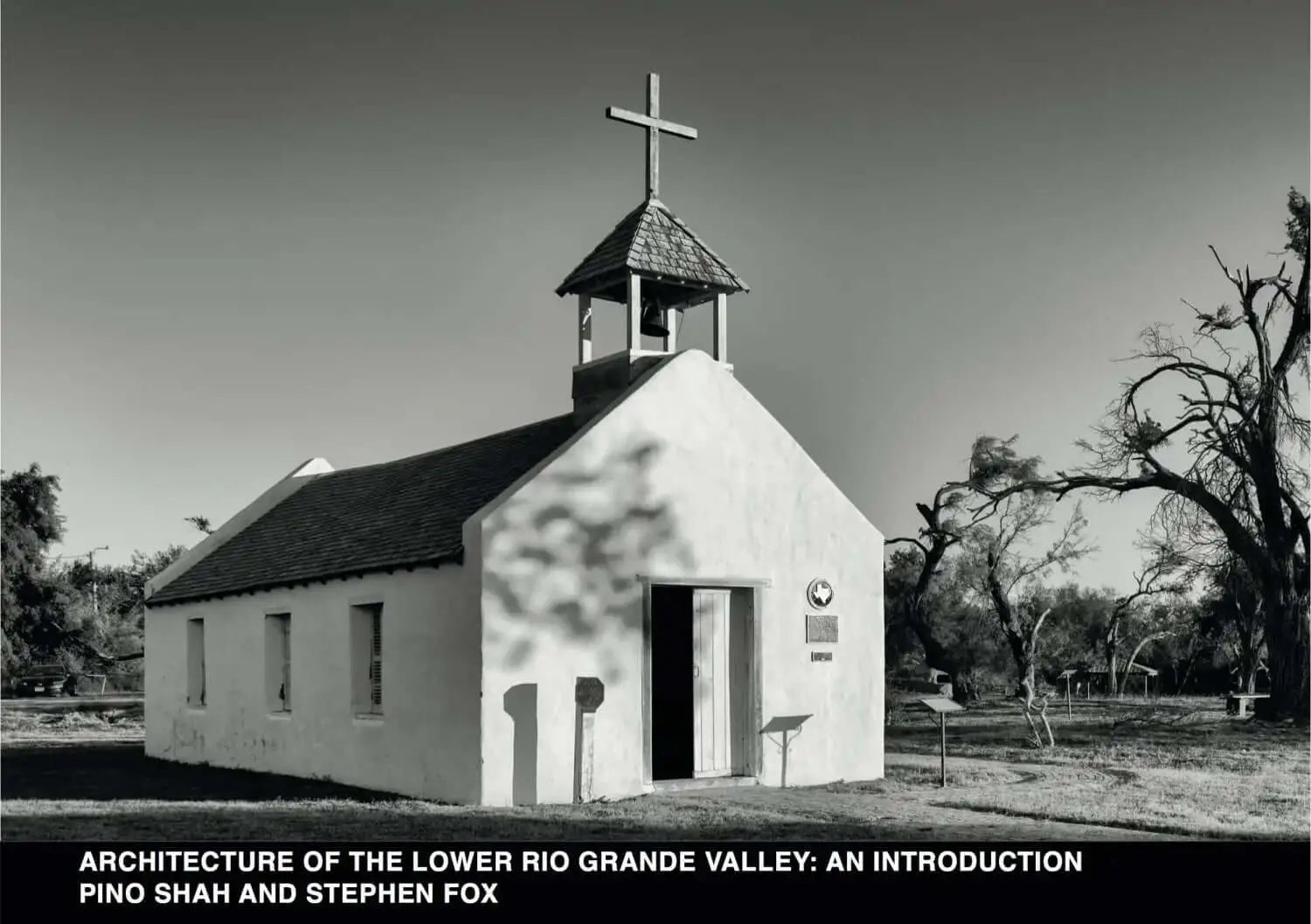White adobe church with a bell tower topped by a cross.