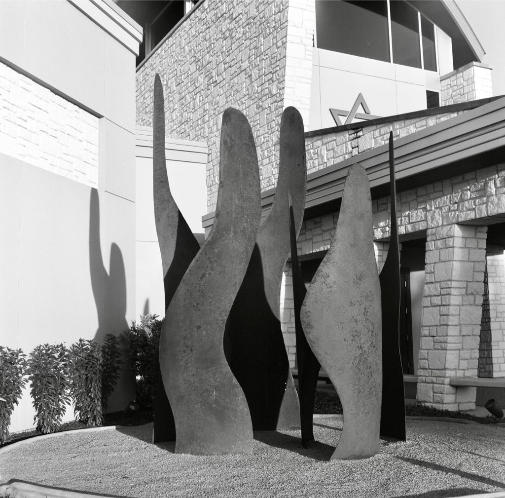 Metal flame-like cactus sculpture in the courtyard at Temple Emanuel, McAllen, with a Star of David on the stone wall, shot on Arista 100 120 film, developed in standard black-and-white chemistry