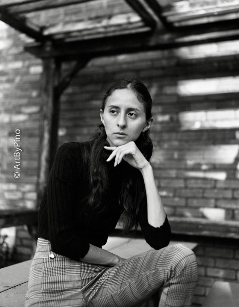 young woman in a dark turtleneck resting her chin on her hand on a patio shot on FOMA Fomapan 100 4x5" large format black and white film