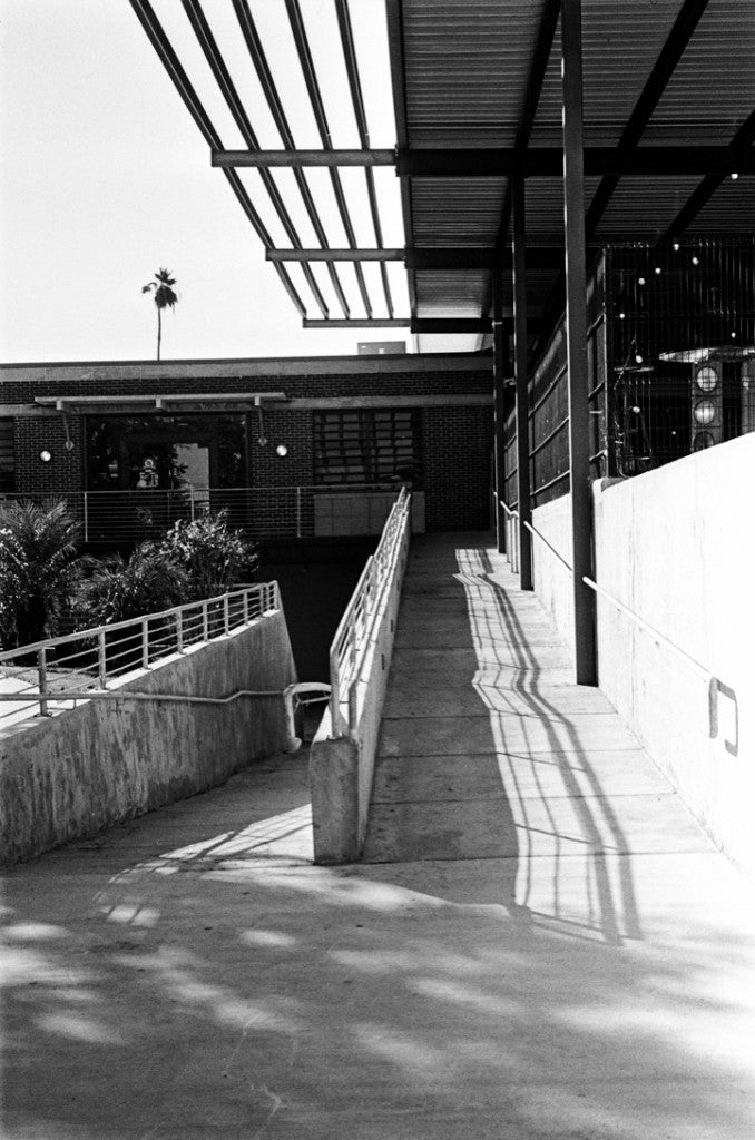 Concrete ramps with dramatic metal-slat shadows and a distant palm, Kodak Ektar H35N + Film Photography Project Wolfman 100 + 35mm half-frame