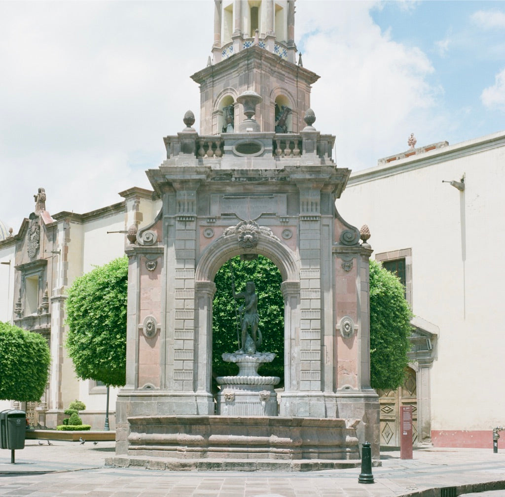 Fuente de Neptuno pavilion with Neptune under the arch and the tiled bell tower of Templo de Santa Clara de Asís, Santiago de Querétaro, shot on Fujifilm Fujicolor PRO 400H 120 film, developed in Kodak C-41