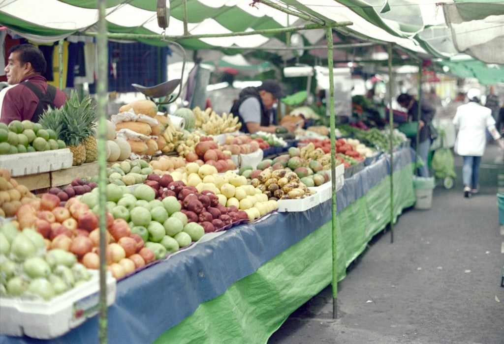 Pentax K1000 / 35mm + Kodak Vision3 200T + Produce market stall with apples, papayas, and striped awning