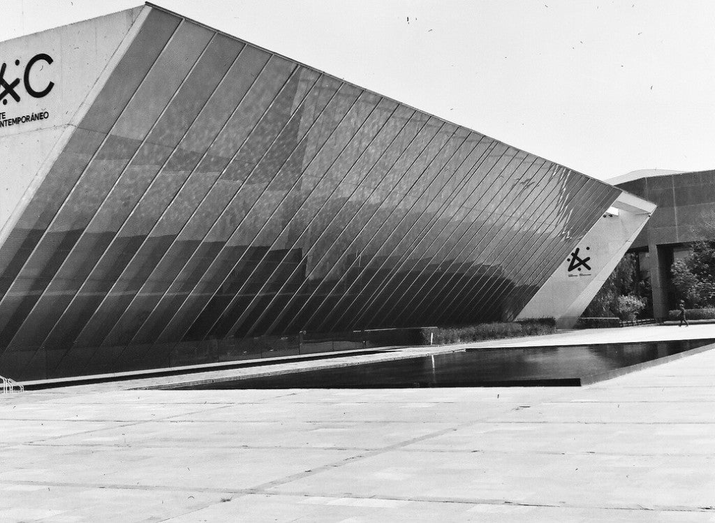 Fachada de vidrio angular y estanque reflectante en el MUAC, Museo Universitario Arte Contemporáneo, UNAM, Ciudad de México, fotografiada con película Lucky SHD 400 120, revelada con química estándar en blanco y negro.