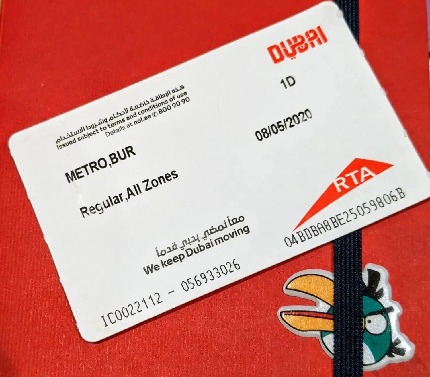 White plastic dubai metro one-day ticket with red branding and black text.