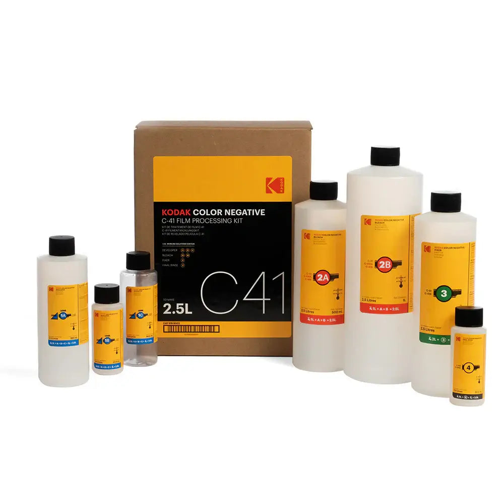 Kodak c41 color negative film processing kit with assorted bottles of chemical solutions in clear plastic containers and black caps, labeled with yellow and colored bands indicating solution numbers.