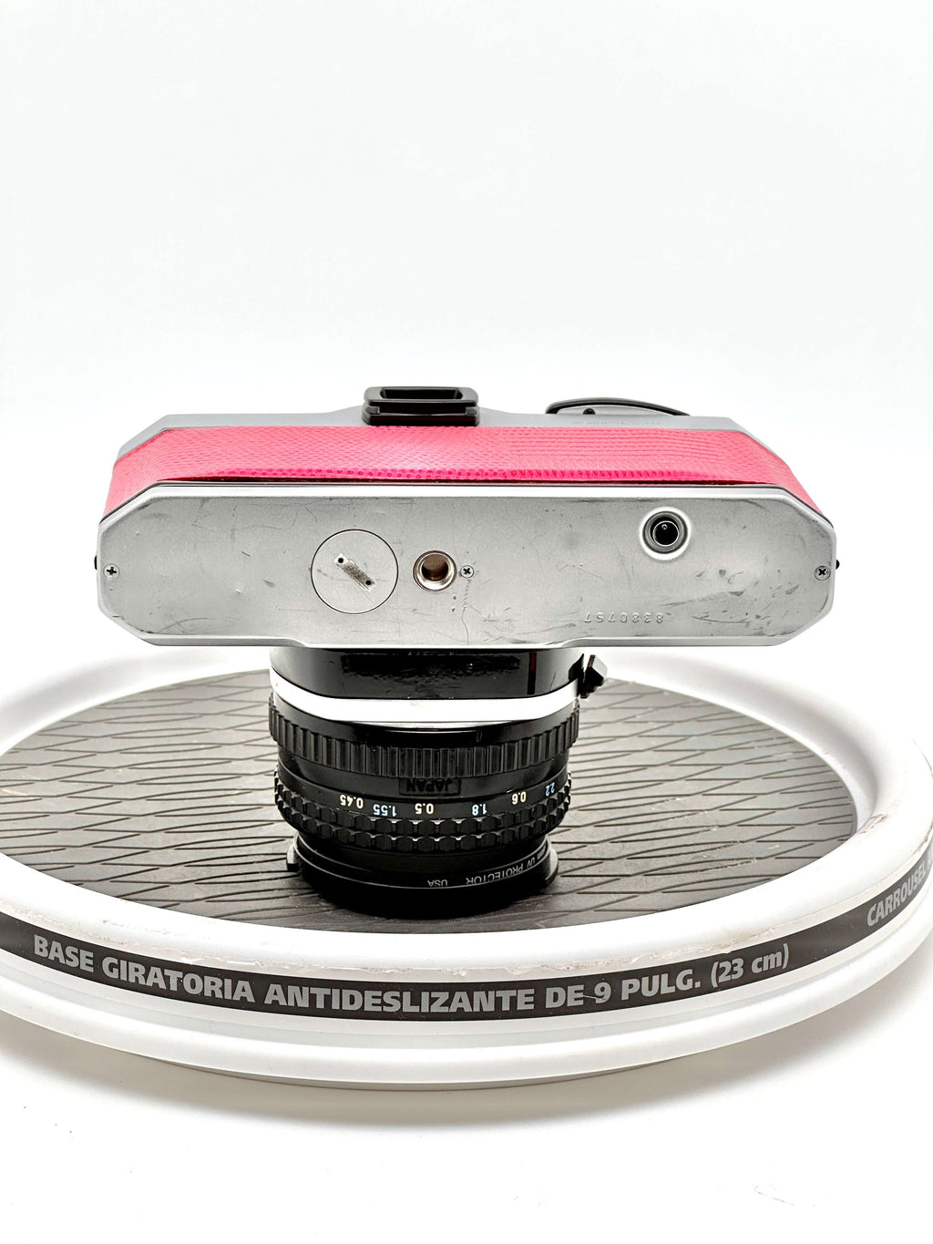 Pink leather-bodied vintage camera with a silver metal top plate and black lens.