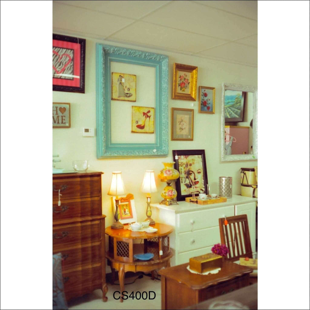 A decorative turquoise picture frame with an ornate, carved design.