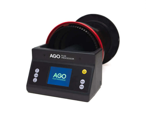Black ago film processor with a red and black film canister slot, featuring a digital display screen and control buttons.