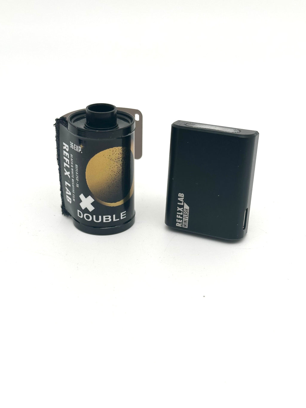 Black reflex lab double film canister with gold circular design and a matching black rectangular battery pack.