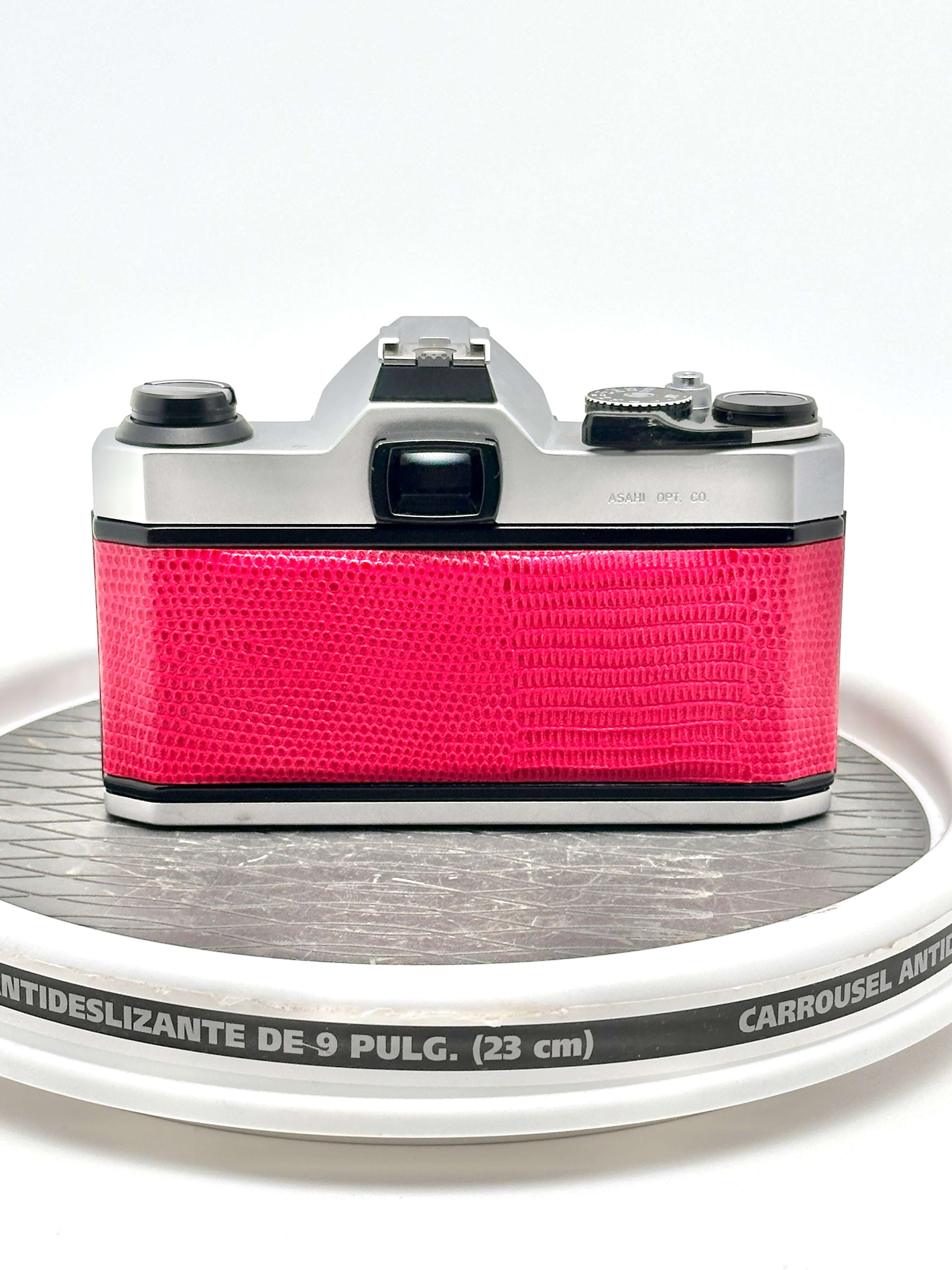 A vibrant pink crocodile-patterned body with silver metallic top and side panels, featuring a classic film camera design.