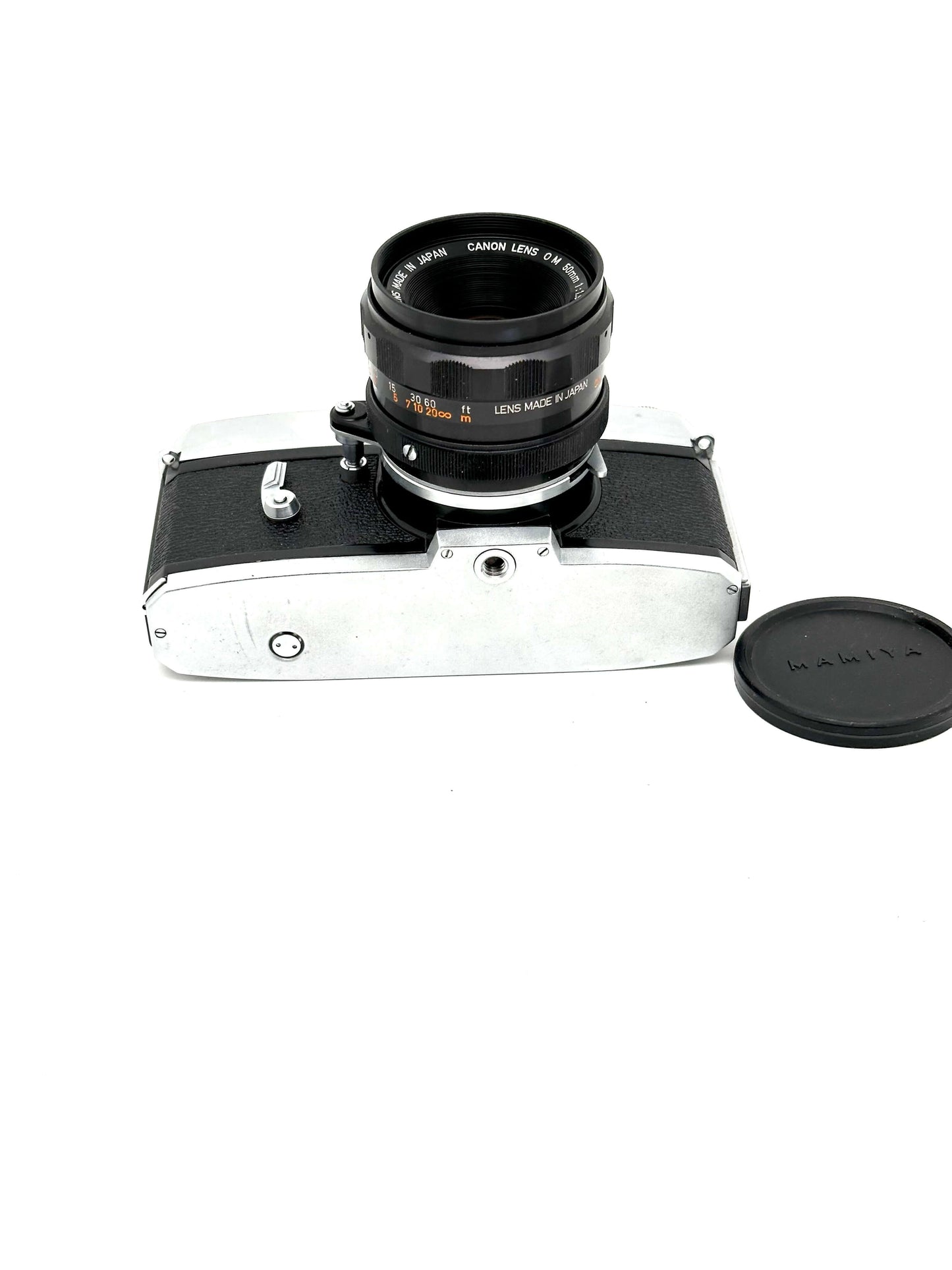 Vintage Mamiya camera with lens and lens cap on a white background