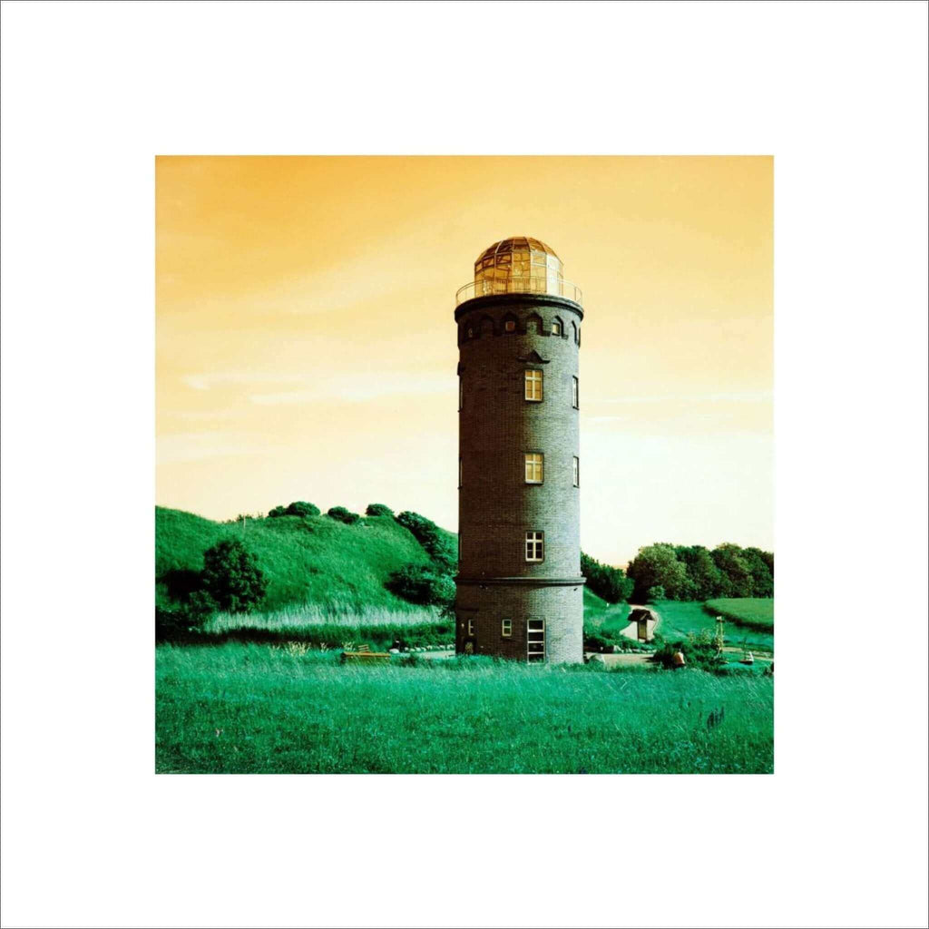 A tall, cylindrical stone tower with a domed top and small windows stands in a lush green field under a warm orange sky.