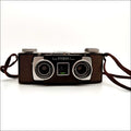 Brown leather-bodied kodak stereo camera with two silver-rimmed lenses and a matching brown strap.