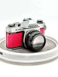 Silver and red textured leather pentax k1000 film camera with a black lens.