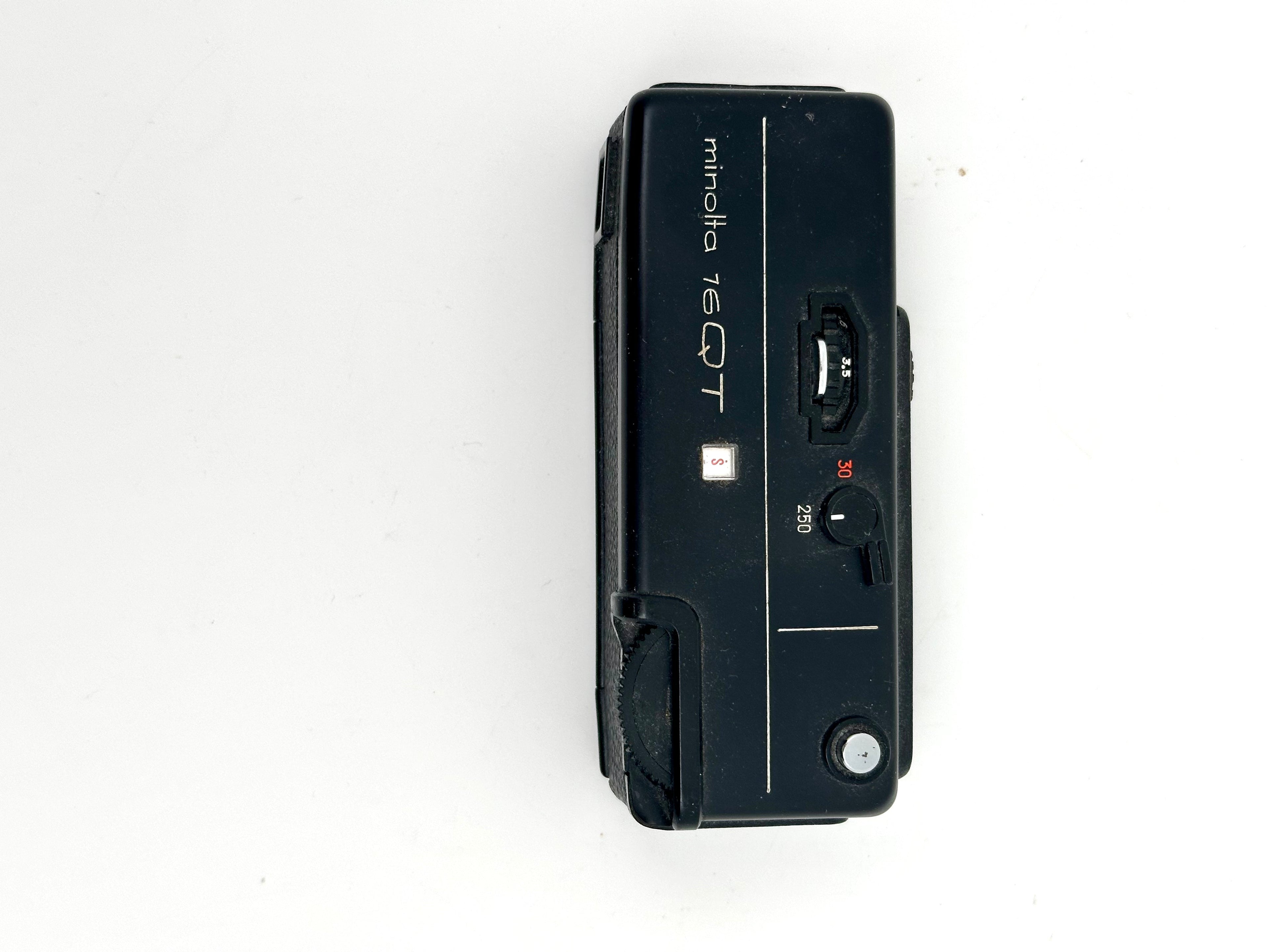 Black minolta 7eqt film camera with a compact, rectangular body and visible dials for shutter speed settings.