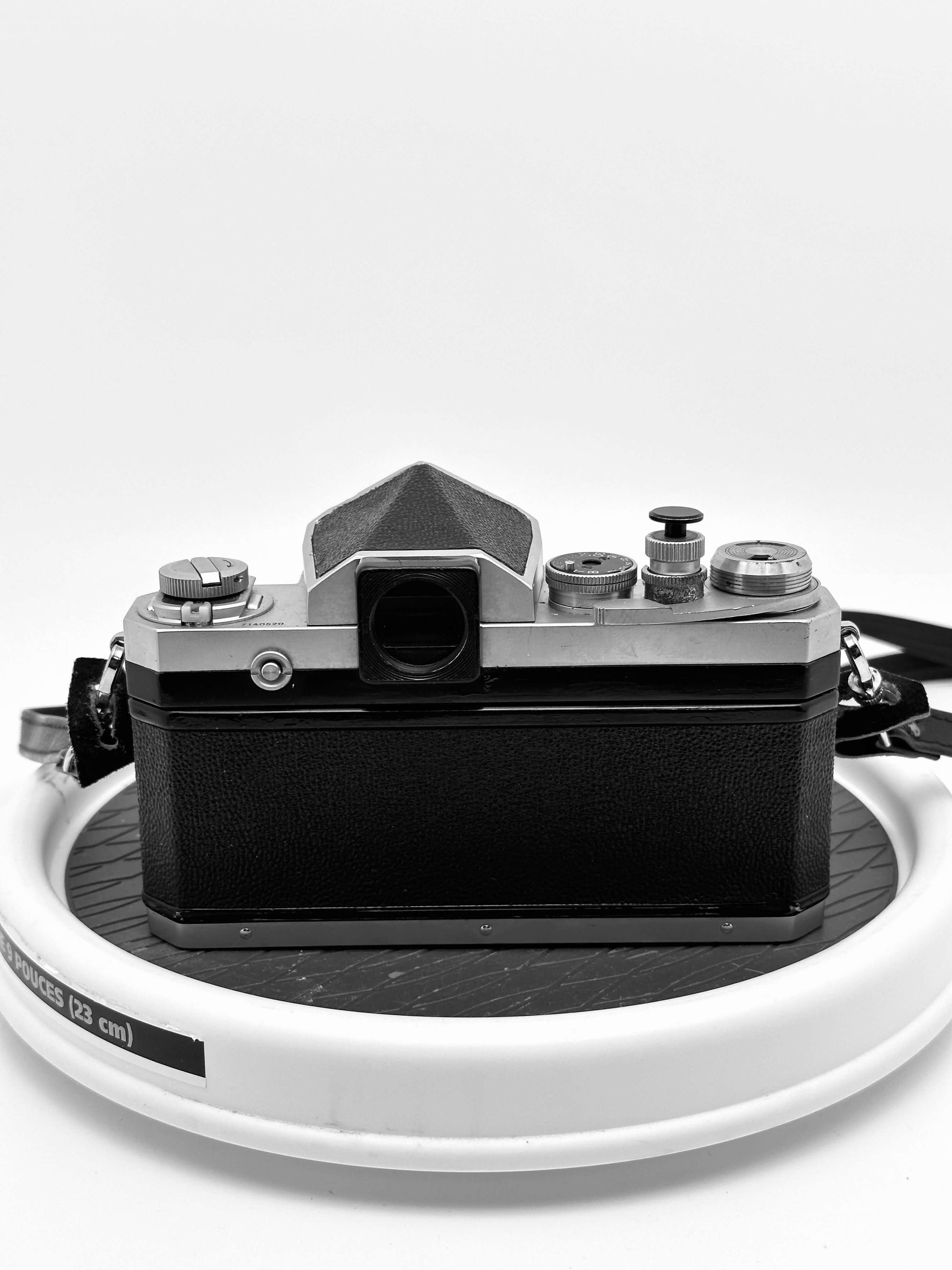 Vintage Nikon F 35mm film camera with Nikkor 43-86mm f/3.5 lens, showing back view, used condition, displayed on a circular stand