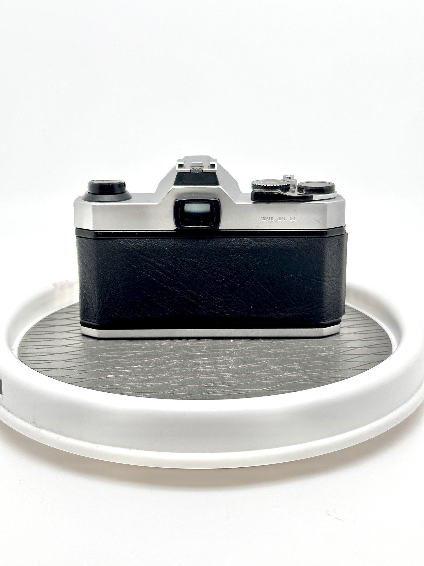 Rear view of a Japanese Asahi Pentax K1000 Black used 35mm film camera on a rotating display.