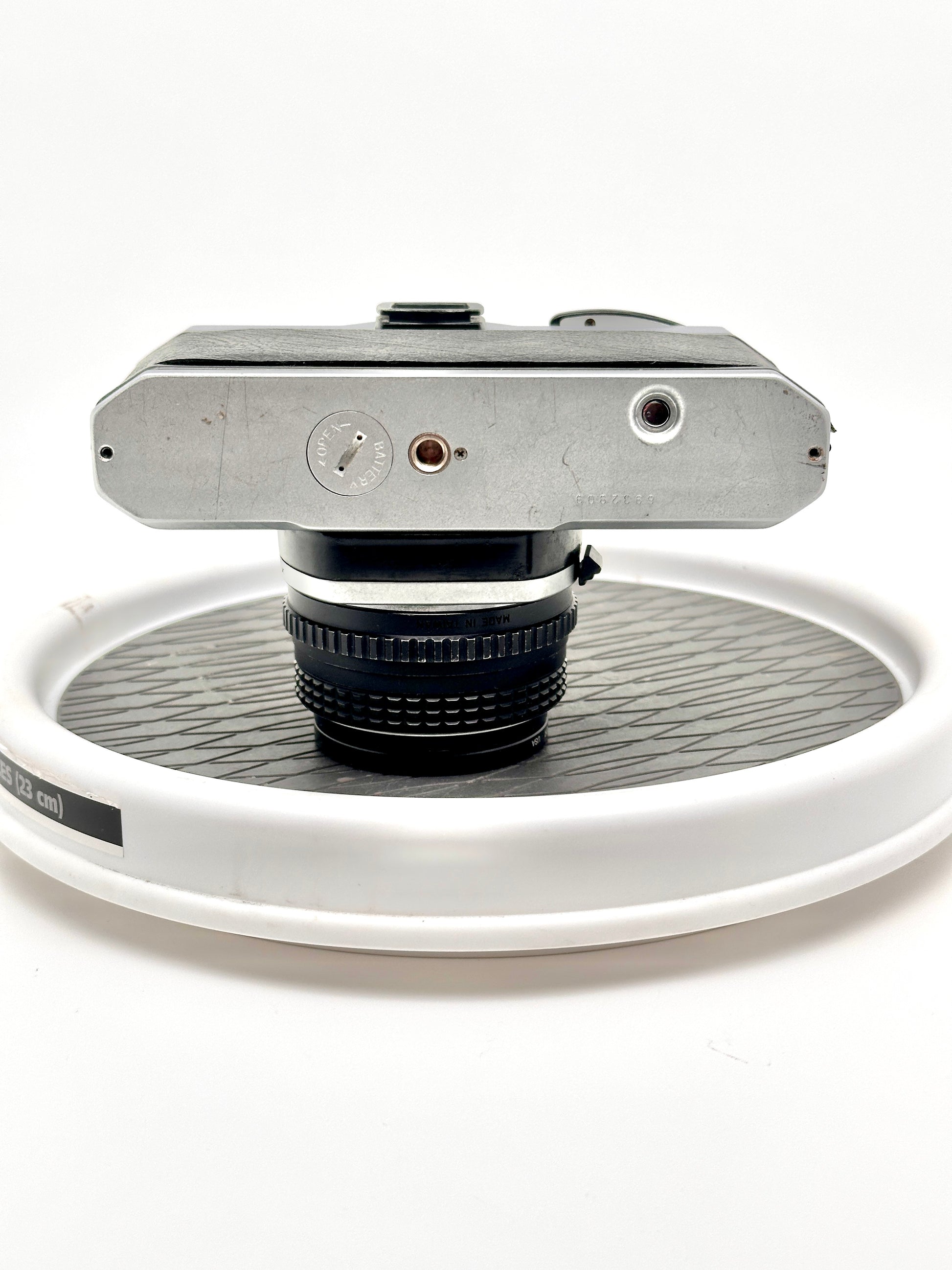 Top view of used Japanese Pentax K1000 35mm film camera with 50mm f2 lens on a circular display.