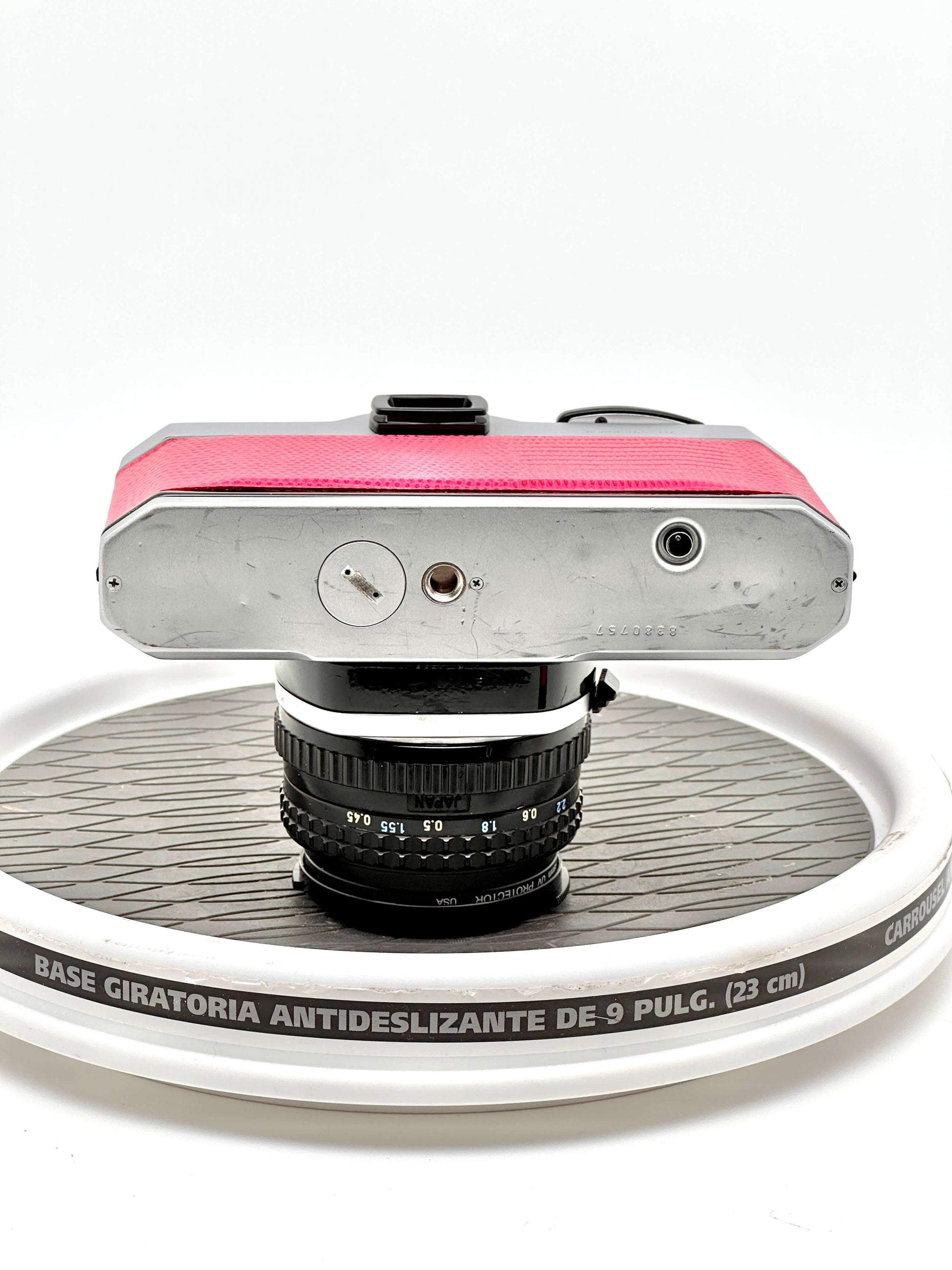 Top view of a used Japanese Asahi Pentax K1000 red 35mm film camera with 50mm f1.7 lens on a circular display base.