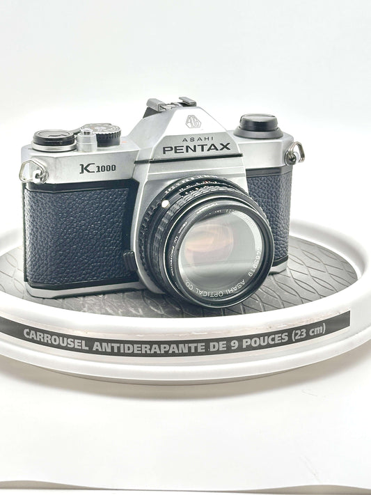 Asahi Pentax K1000 used 35mm film camera with 50mm f2 lens on display. Iconic design and reliable performance for photography enthusiasts.