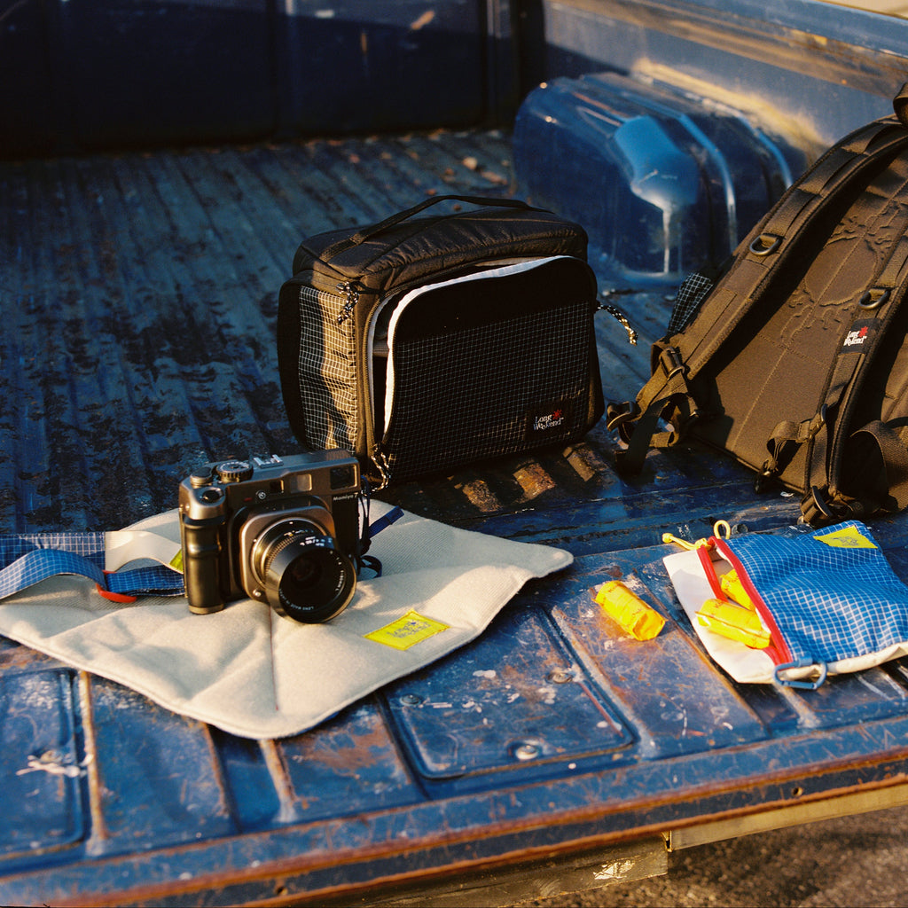 Long Weekend padded camera wrap unfolded as a mat under a film camera on a truck tailgate