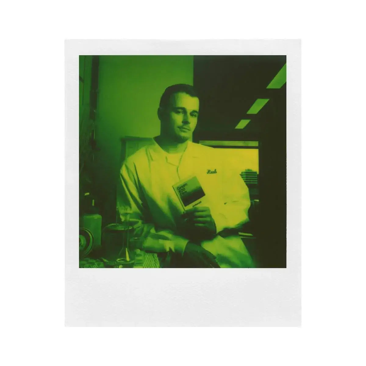 Polaroid Green 600 Instant Film photo of a person holding a book, featuring a distinctive green hue and white frame from the Reclaimed Series.