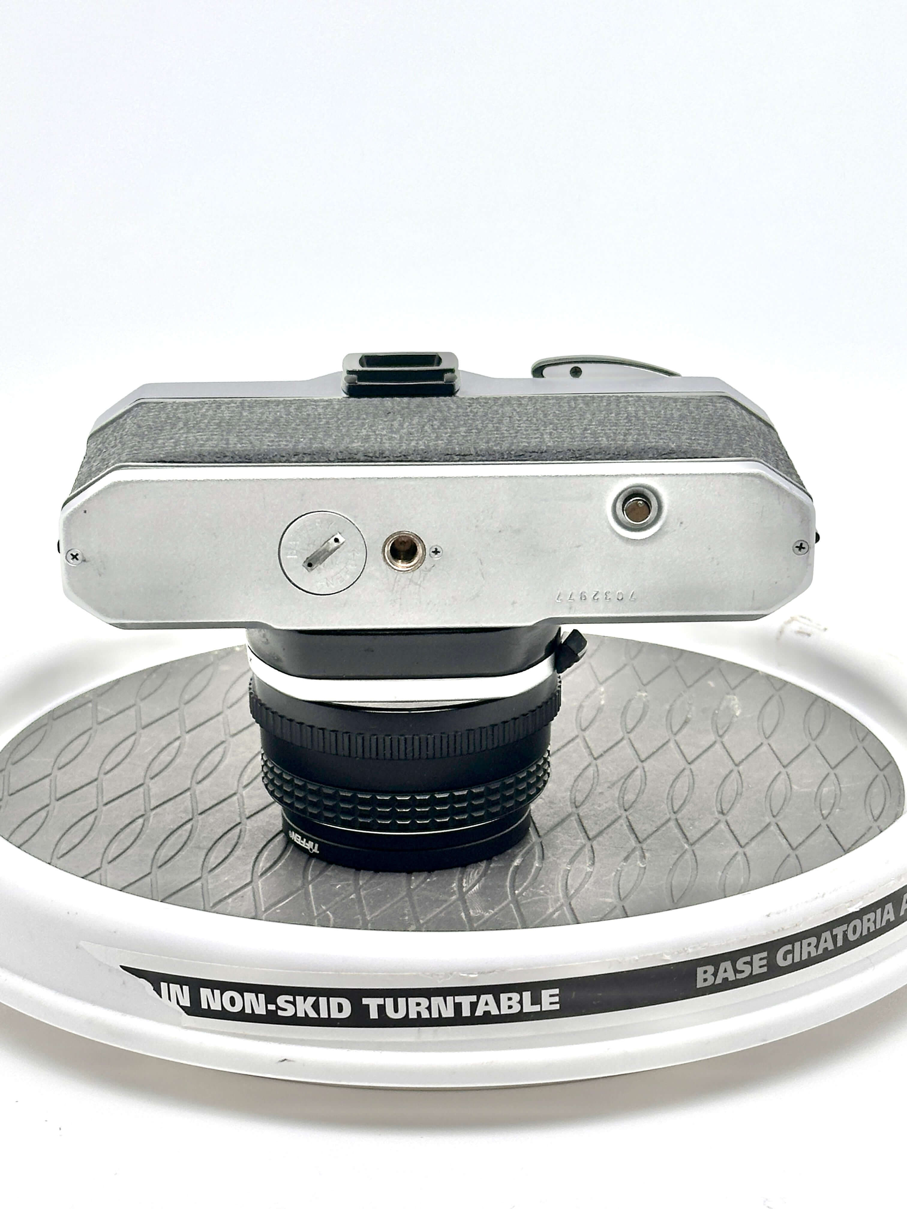 Silver-bodied vintage camera with textured grip and black lens mounted on a turntable.