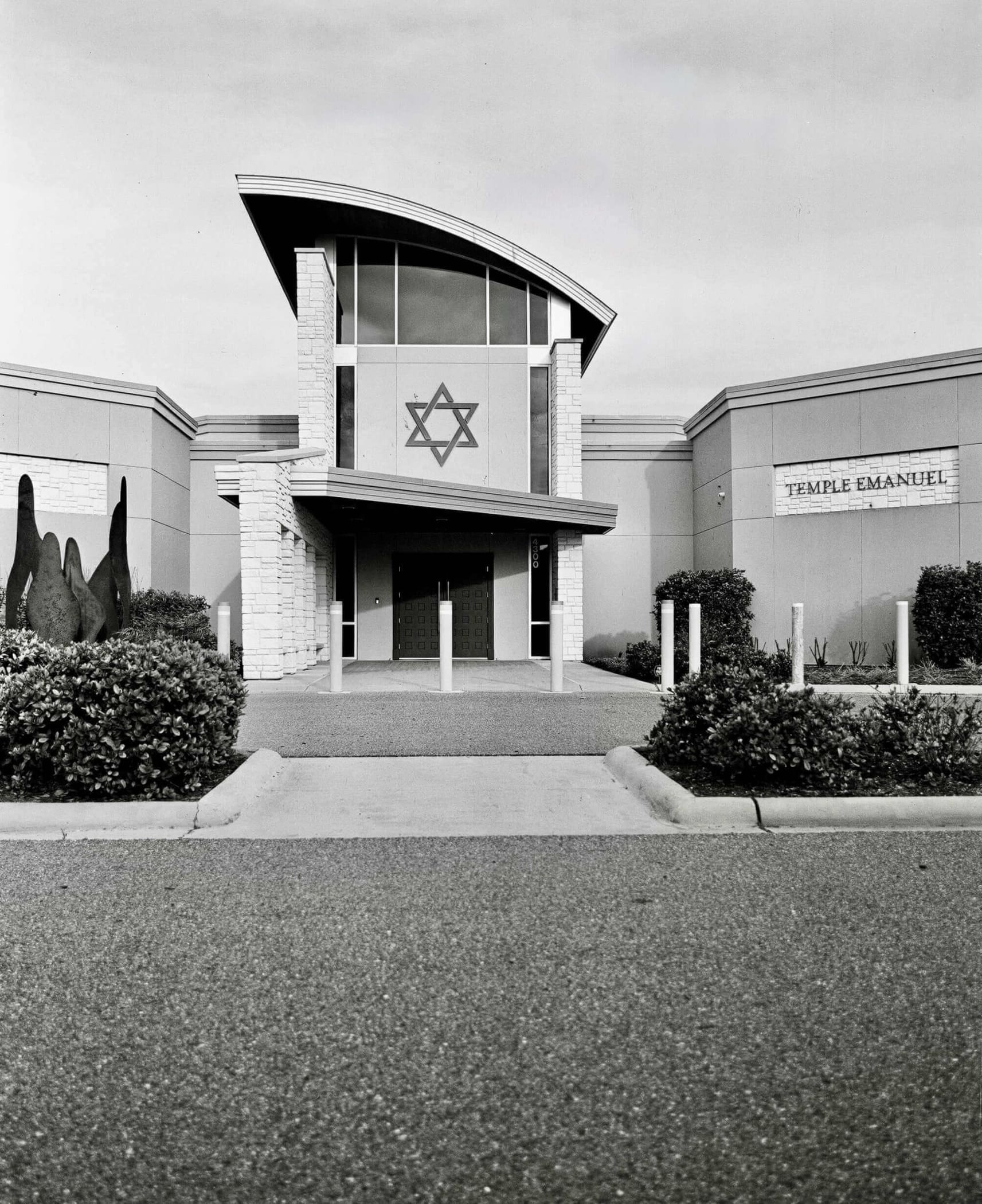 The main object is a modern synagogue building with a prominent star of david emblem on its facade, constructed from light-colored stone and featuring large arched windows.