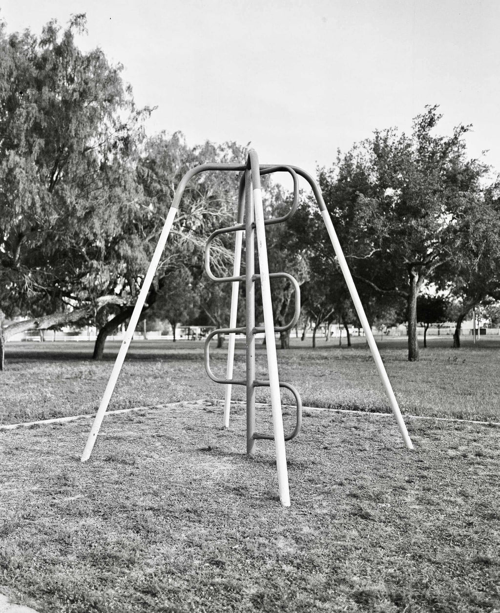 Metallic playground climbing frame with curved rungs and diagonal support beams.