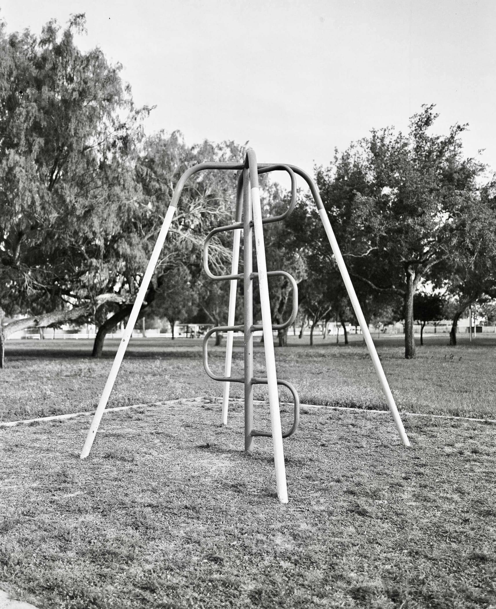 Metallic playground climbing frame with curved rungs and diagonal support beams.