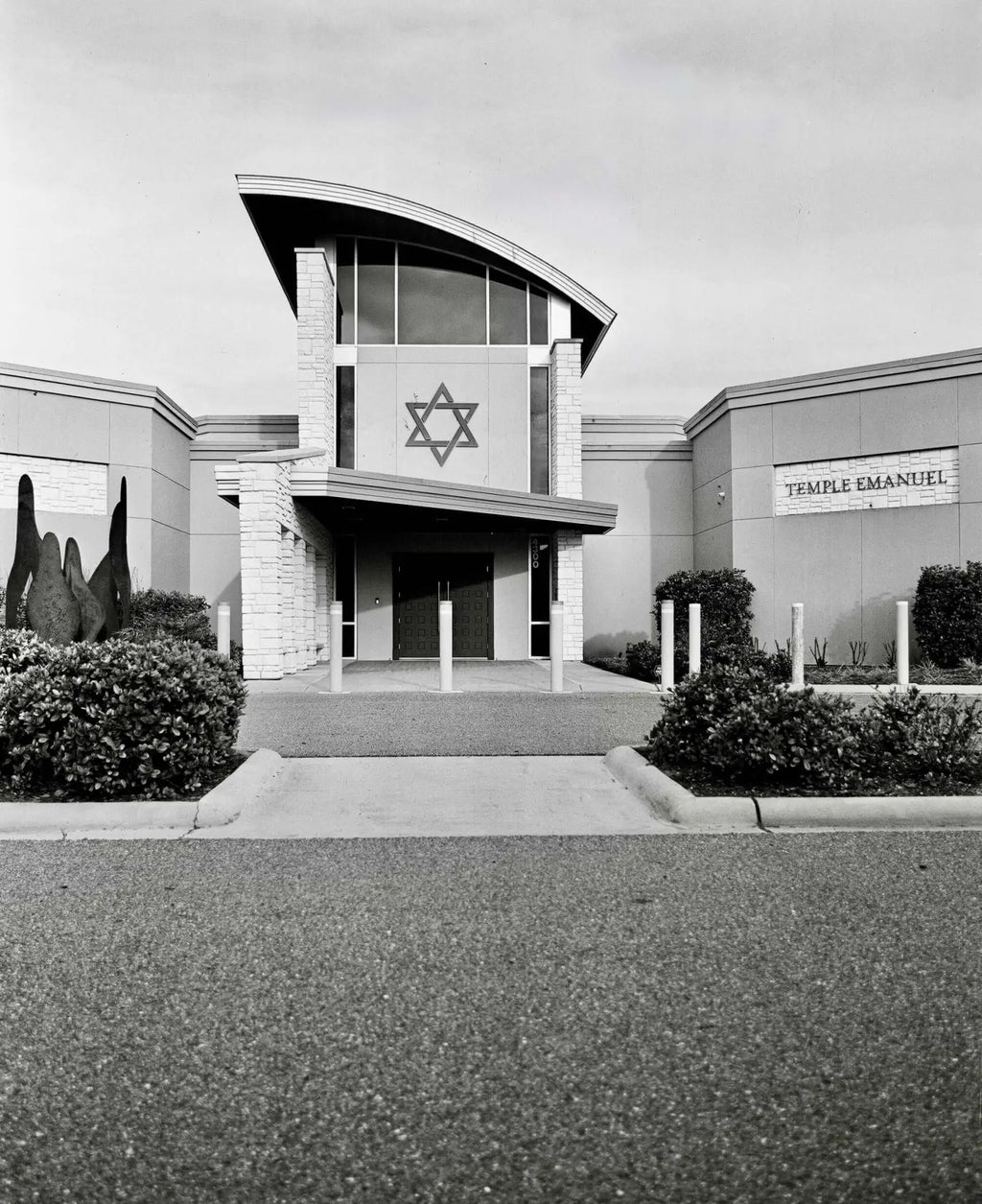 The main object is a modern synagogue building with a prominent star of david emblem on its facade, constructed from light-colored stone and featuring large arched windows.