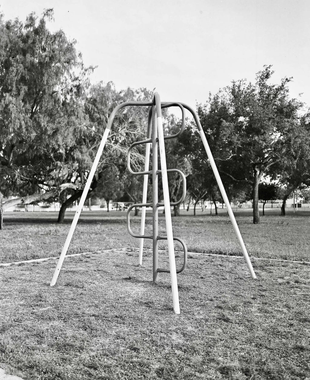 Metallic playground climbing frame with curved rungs and diagonal support beams.