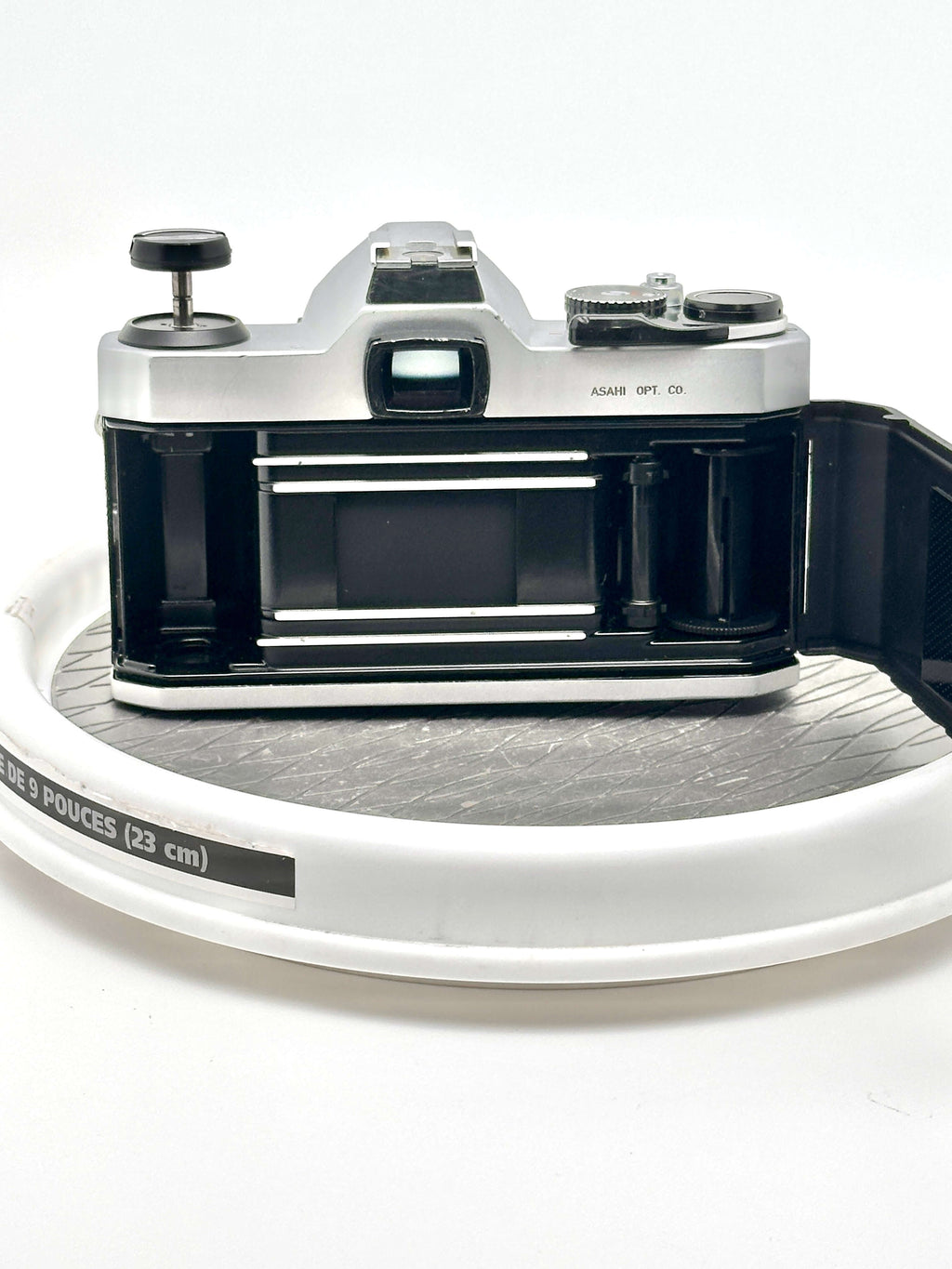 Pentax K1000 black 35mm film camera rear view on a white display turntable.