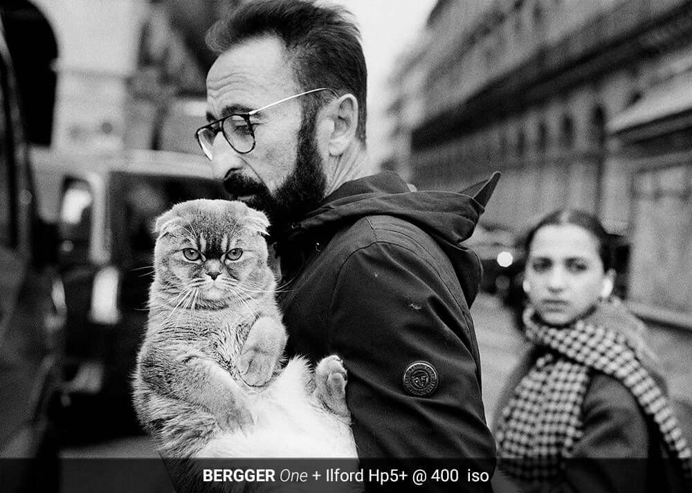 Man holding cat on city street developed with BERGGER ONE and Ilford Hp5+ film at 400 ISO