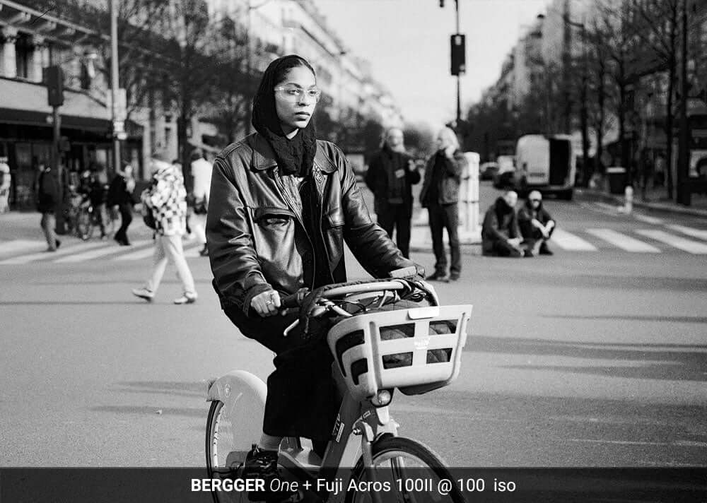 Person riding a bicycle in a city captured using BERGGER ONE and Fuji Acros 100II film.