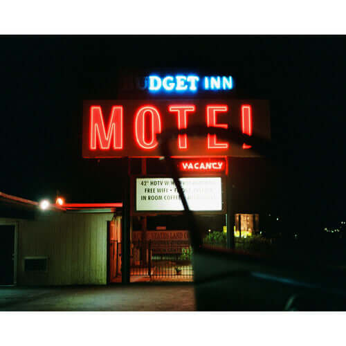 Bright neon sign of Budget Inn Motel with vacancy at night, showcasing colorful lights and retro design.