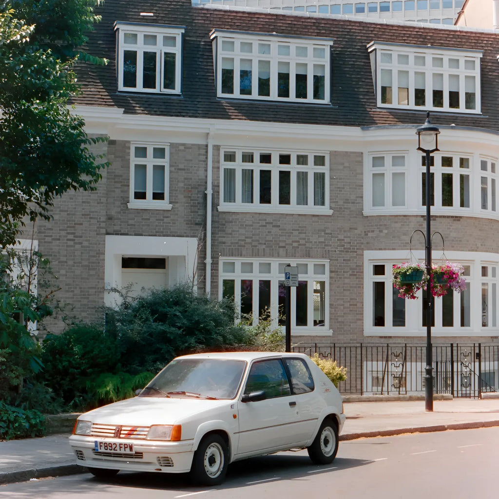 White peugeot 205 hatchback parked on street captured on candido c41 color 800 iso 35x36 35mm color negative film