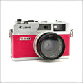 A vibrant pink and silver canon g-iii ql film camera with a textured finish.
