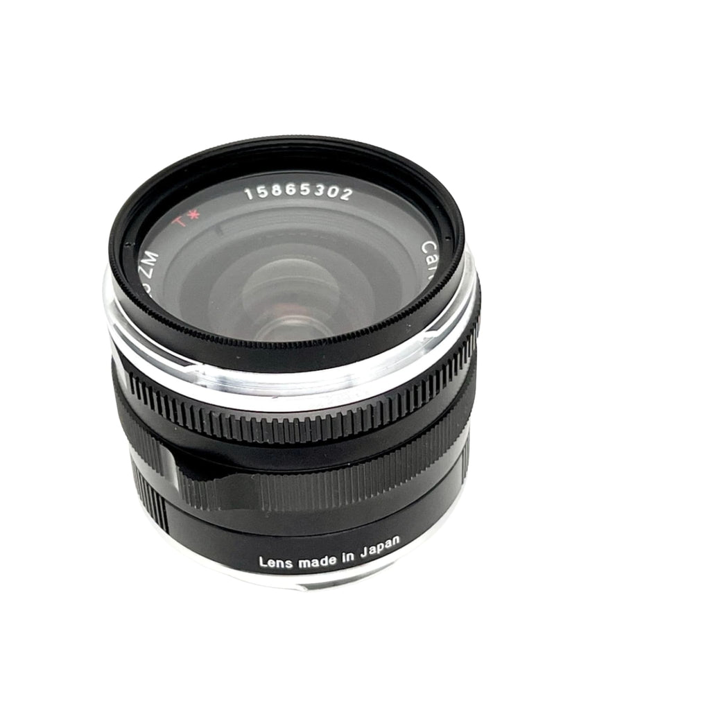Black and silver canon zm lens with a textured focus ring, marked ’lens made in japan’ on its base.