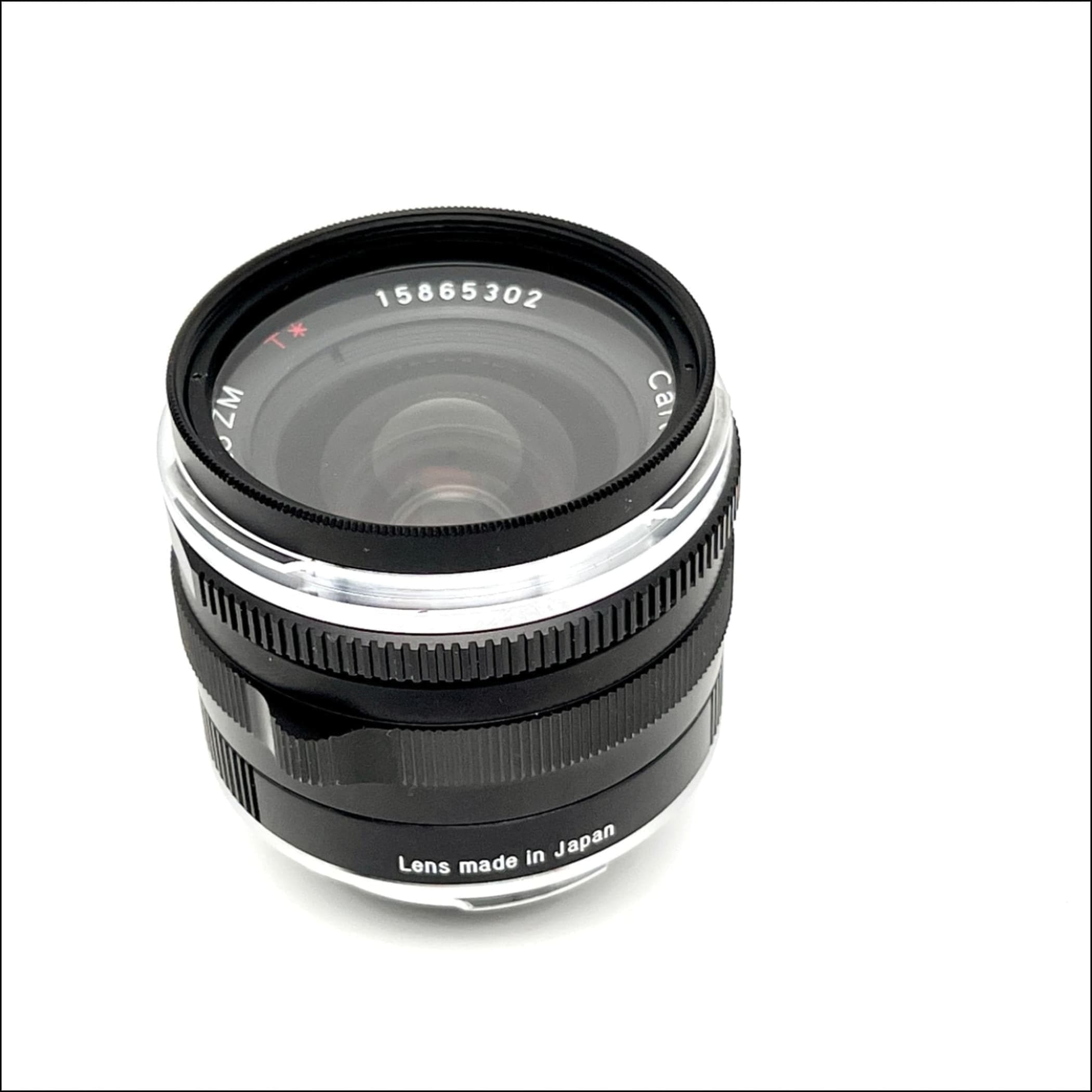 Black and silver canon zm lens with a textured focus ring, marked ’lens made in japan’ on its base.