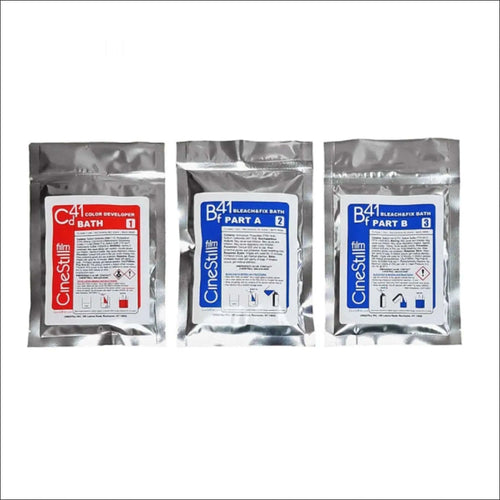 Three silver foil packets of cinestill film processing chemicals, labeled as color developer bath 1 and bleach/fix bath parts a and b.