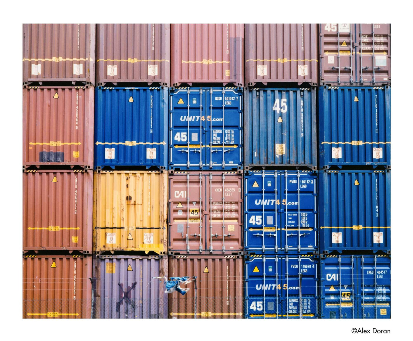 Colorful stacked shipping containers in a grid pattern, showcasing various hues and textures.