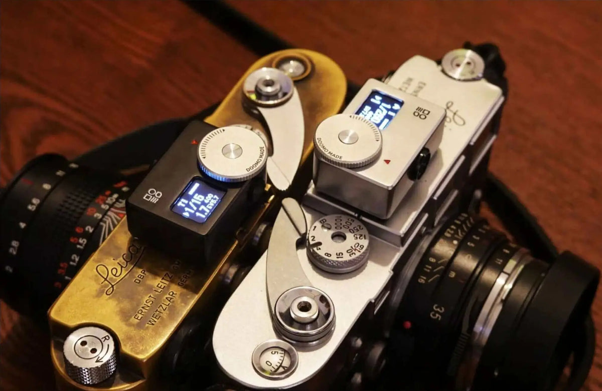 Silver and gold leica rangefinder cameras with attached digital viewfinders.