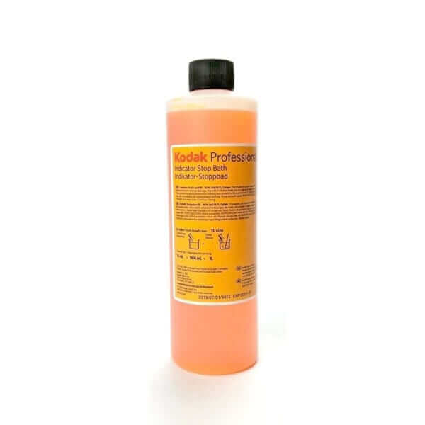 Orange liquid-filled bottle with black cap and yellow label reading ’kodak professional indicator stop bath.’