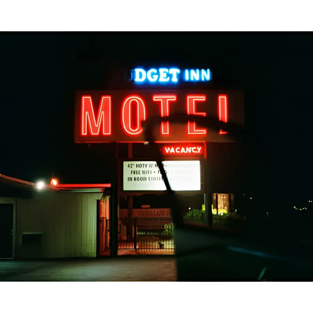 The glowing red neon sign for the dget inn motel, with a smaller blue ’dget inn’ above and a yellow ’vacancy’ below.