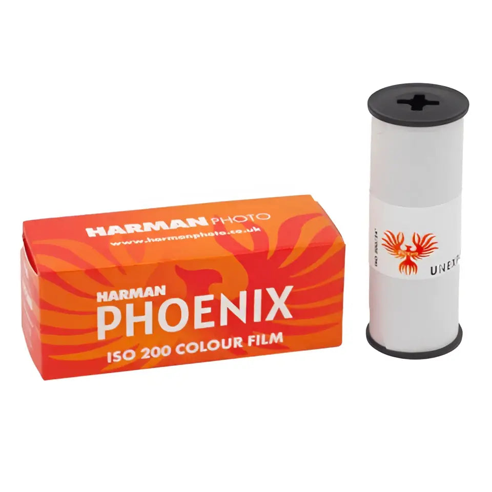 Harman phoenix iso 200 colour film in a vibrant orange box with fiery red and yellow swirls, packaged alongside its white cylindrical roll featuring an embossed phoenix logo.